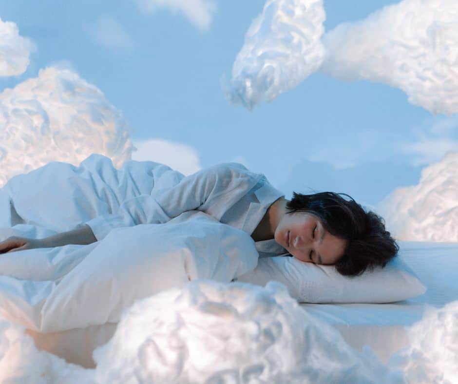 אישה ישנה במיטה עם עננים מעליה.